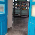 Entrance to a rural Vietnamese school library with worn floors and nearly empty bookshelves visible behind the door